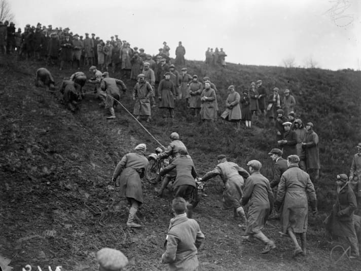 March 1927: A participant in the Southern Scott Motor Cycle Reliability Trial is pulled up a muddy slope by a rope.