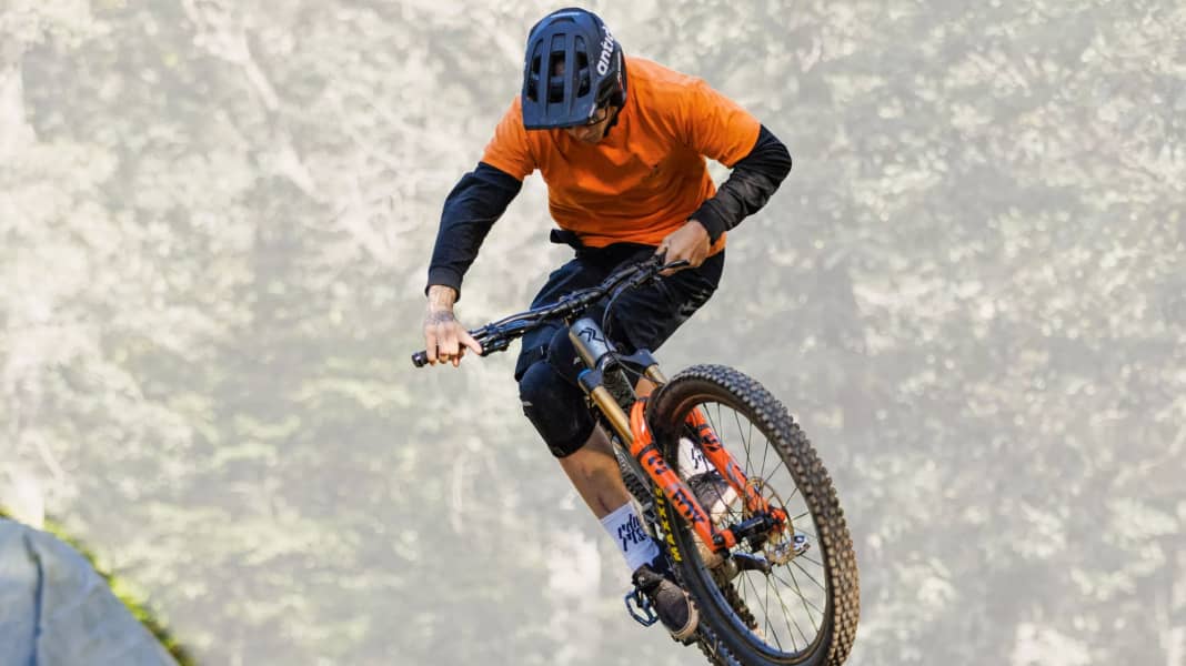 Der lenker eines mountainbikes in der werkstatt auf schwarzem hintergrund  austausch des schaltseils im fahrrad der mechaniker hält ein neues seil in  der hand