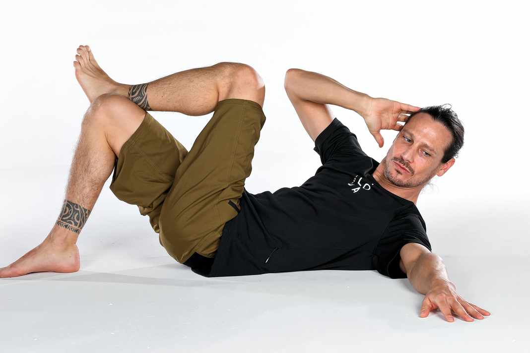 The gaze guides the movement. The elbow touches the knee.