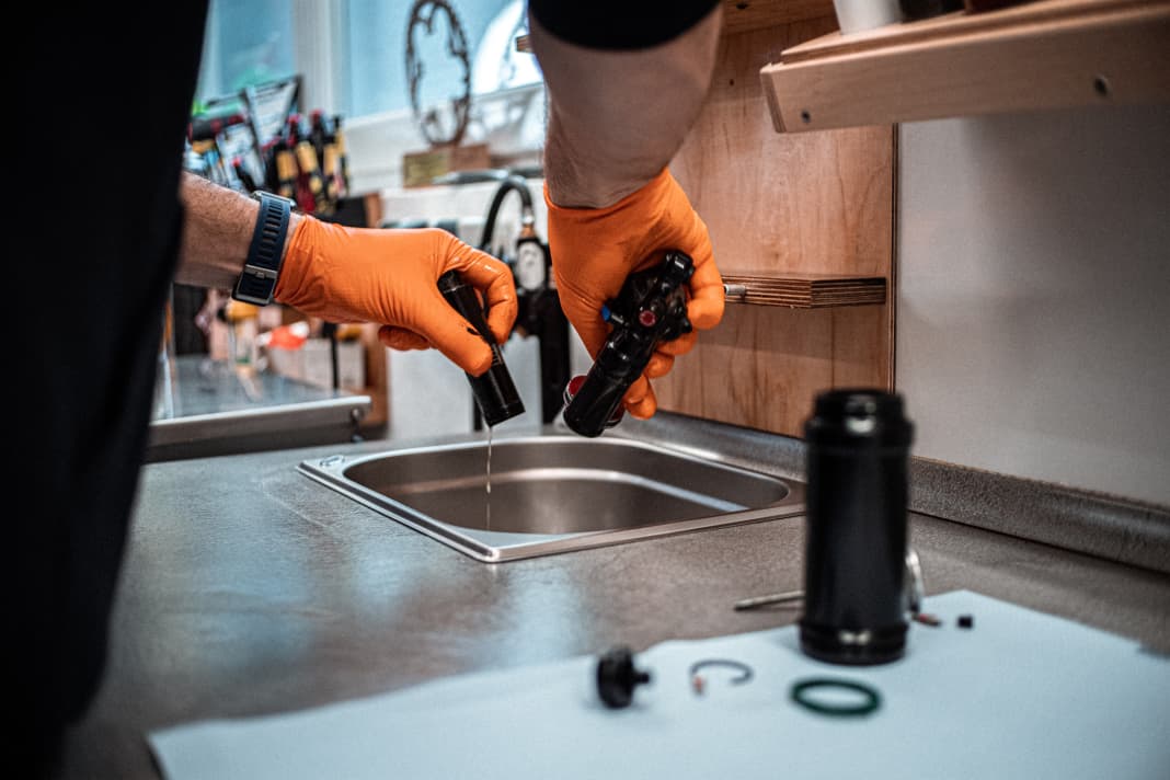 Once the shock has been removed from the bike, it is disassembled further. Take care: Excess oil must be disposed of properly. Marcus Klausmann has a sink connected to a waste oil container for this purpose. Everyone else prefers to tip the stuff directly into appropriate bottles.