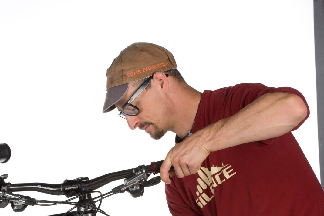 Sitzt der Bremssattel schief, schleifen die Beläge an der Scheibe und nutzen sich ungleichmäßig ab. Ziel ist es, dass auf beiden Seiten der Bremsscheibe ein minimaler Abstand zu den Belägen bleibt. Bei der Montage mit IS2000-Standard erreichen Sie dies mit hauchdünnen Unterlegscheiben, die im Lieferumfang der Bremse enthalten sind (ansonsten im Fachhandel). Deutlich einfacher funktioniert die Justage bei Bremsen mit Langlochbefestigung, da die sogenannte Postmount-Befestigung Korrekturen erlaubt. Lösen Sie hierzu die Schrauben für den Bremssattel so weit, dass dieser sich bewegen lässt. Ziehen Sie nun den Bremshebel, die Bremse richtet sich automatisch mittig an der Scheibe aus. Halten Sie den Bremshebel weiter fest, während Sie die beiden Schrauben wieder vorsichtig festziehen.
