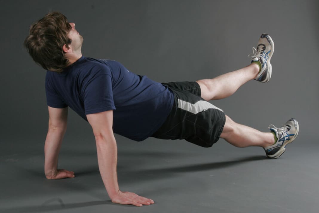 Kräftigung der Rücken- und Hüftstrecker sowie der schrägen Bauchmuskulatur. Setzen Sie sich mit gestreckten Beinen hin. Die Hände neben das Gesäß, wobei die Finger leicht nach außen zeigen. Drücken Sie sich hoch. Ziehen Sie dabei die Schulterblätter nach hinten in Richtung Wirbelsäule. Ferse und Schultern sollten eine Gerade bilden. Wer die Belastung steigern möchte, kann ein Bein anheben. Achtung: dabei die Hüfte nicht abkippen lassen.