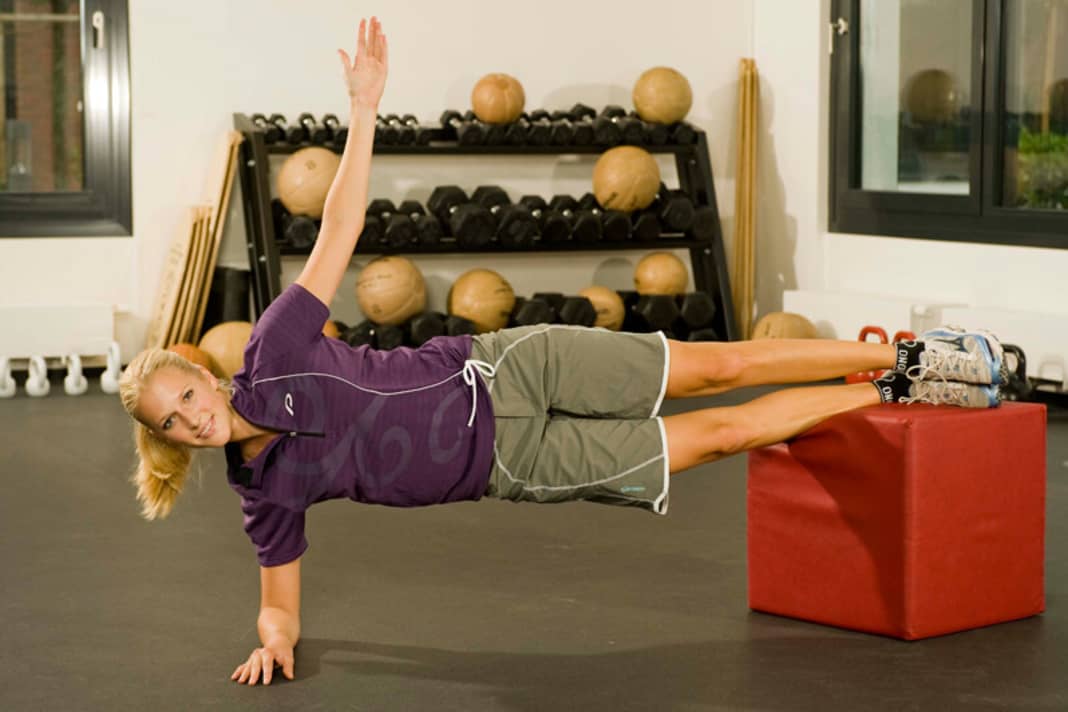 1. side support on box
Lie on your side and place your feet on top of each other on a chair or stool. Viewed from above, your body forms a line. Now raise your hips to the maximum and stretch your upper arm upwards.