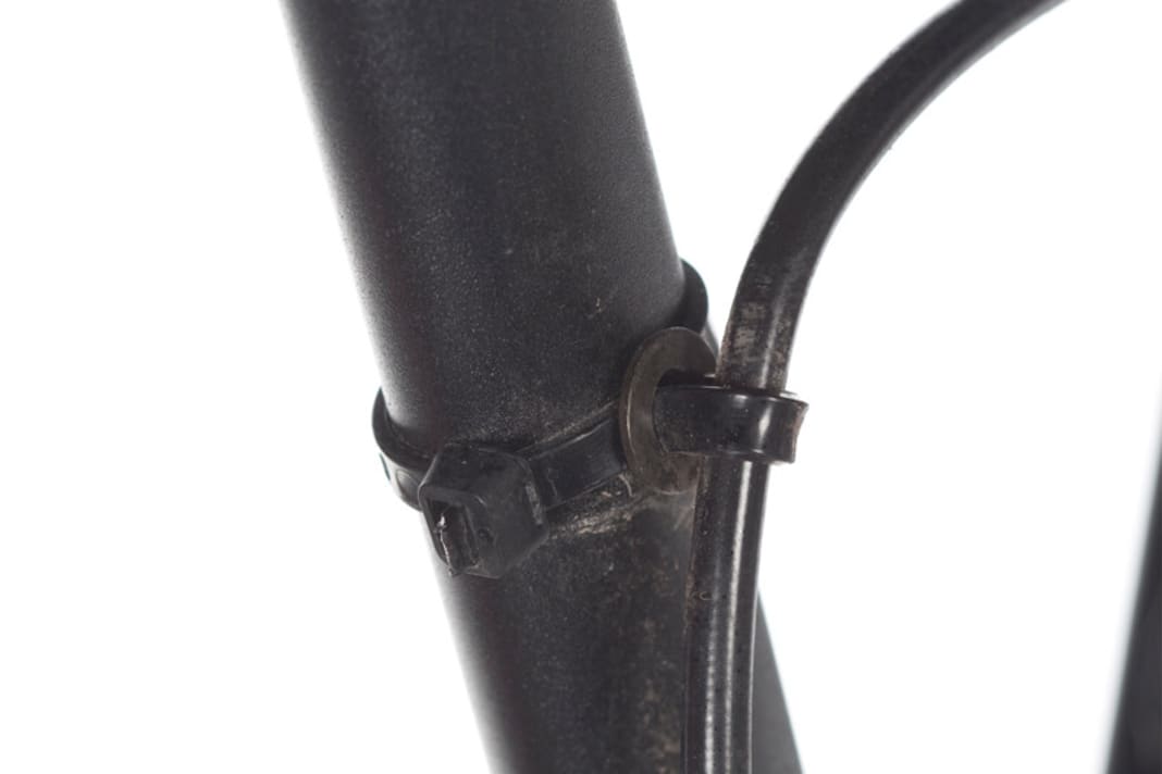 Die Bremsleitung muss am Hinterbau von Fullys wegen des Einfederns beweglich montiert sein. Trick: Fädeln Sie einen Kabelbinder durch eine M5-U-Scheibe. Der Kabelbinder sollte locker um die Bremsleitung liegen. So wird er optimal geführt, bleibt aber an Ort und Stelle.