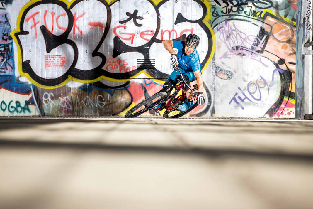 Wofür?: Nur so kannst Du Dein Bike um enge Kurve zirkeln. Achtung: So schräg, wie ich mein Bike hier in die Kurve lege, klappt das nur auf griffigem Untergrund. Zum Beispiel auf Teer oder Waldboden. Dafür sollten die Reifen in gutem Zustand sein.

Wie funktioniert’s?: Fahre mit etwas Zug an und lege Dein Rad in die Kurve, indem Du Deinen kurveninneren Arm streckst (siehe Bild). Du selbst bleibst aufrecht. Dein Schwerpunkt ist leicht vorne, so übst Du genug Druck aufs Vorderrad aus und verhinderst, dass die Reifen wegschmieren. Wichtig: Gib viel Druck auf das kurvenäußere Pedal für maximale Traktion.

TIPP: Finde Deine Schokoladenseite. Übe auf einem Parkplatz ohne Hindernisse und taste Dich langsam ran. Etwas Gefälle ist hilfreich, um Geschwindigkeit aufzubauen.