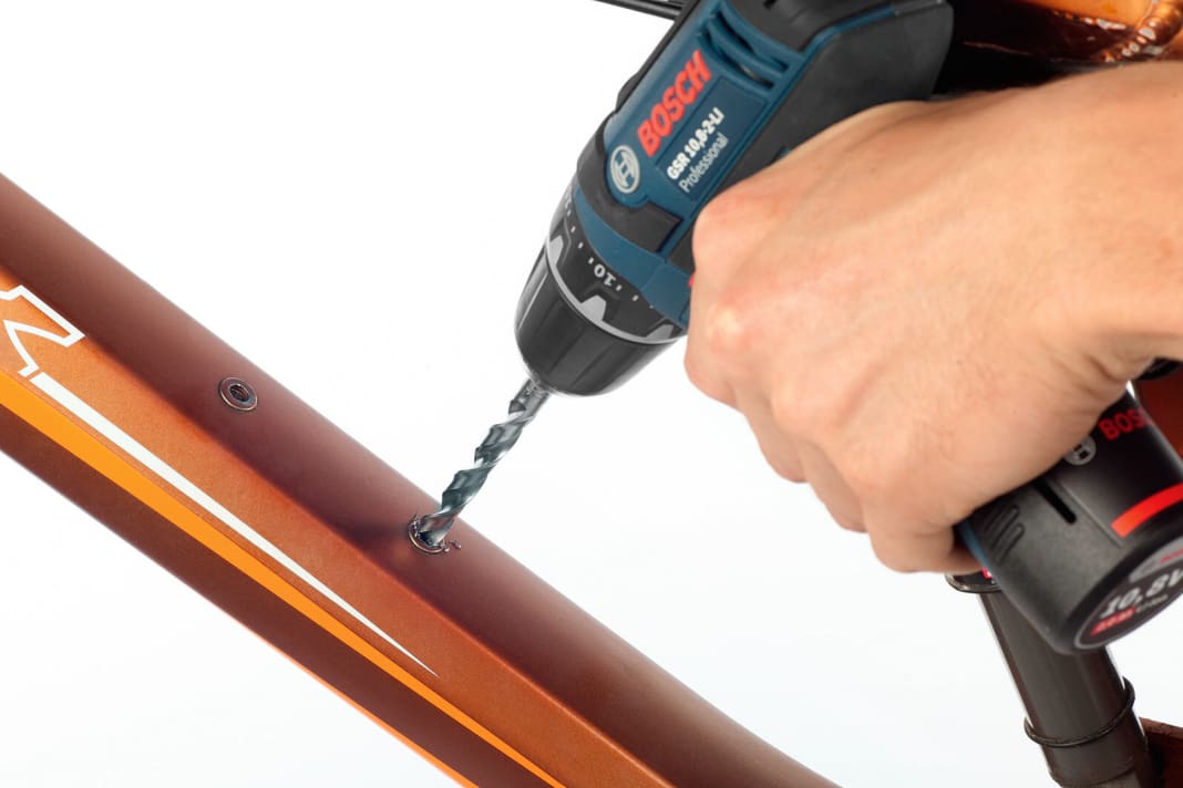 (1) Aufbohren  Bohren Sie die defekte Niete mit einem Siebener-Bohrer auf, bis der defekte Teil ins Innere des Rahmens fällt.