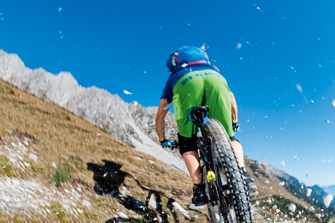 Bremse richtig: Das Hinterrad plump zu blockieren, sorgt für Erosion und für nervige Bremsrillen. Wer seine Bremse im Griff hat, bremst ohne Radstillstand. Das spricht dagegen: Das Hinterrad zu blockieren, beweist nicht nur fehlende Fahrtechnik (nämlich verkrampften Fingereinsatz), sondern schadet auch Trails und Wegen. Bestes Beispiel bei viel befahrenen Trails: Bremswellen vor der Kurve. Warum? Ungeübte Biker greifen zu undosiert in die Bremse, das Rad blockiert und verschiebt den Untergrund: Folge: Erosion, Bremswellen und ein Trail, der sich ungeschmeidig fahren lässt. Kurz: Wer das Hinterrad blockiert, macht den Trail kaputt, schadet anderen Bikern und sich selbst. Wie geht’s richtig? Dosiert bremsen. Zudem hat ein drehendes Rad immer mehr Kontrolle als ein stehendes (ABS-Faktor). Tipp: Lege Dir Fingerspitzengefühl beim Bremseinsatz zu. Z. B. auf steilen Passagen. Negativ-Beispiel: So sehen uns Mountainbike-Gegner gerne. Rowdys, die mit blockiertem Hinterrad Trails schaden und Wanderer vor Schreck zur Seite springen lassen.