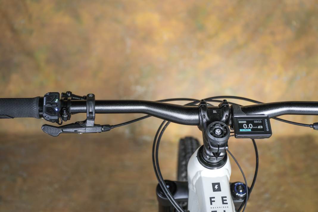 Das Shimano-Display sitzt gegen Sturzschäden gut geschützt hinterm Lenker. Das Cockpit wirkt aufgeräumt, die Ergonomie von U-Stufen-Shifter und Telestützen-Remote gefällt. Mit 170 mm stellt die Rockrider-Stütze reichlich Hub zur Verfügung.