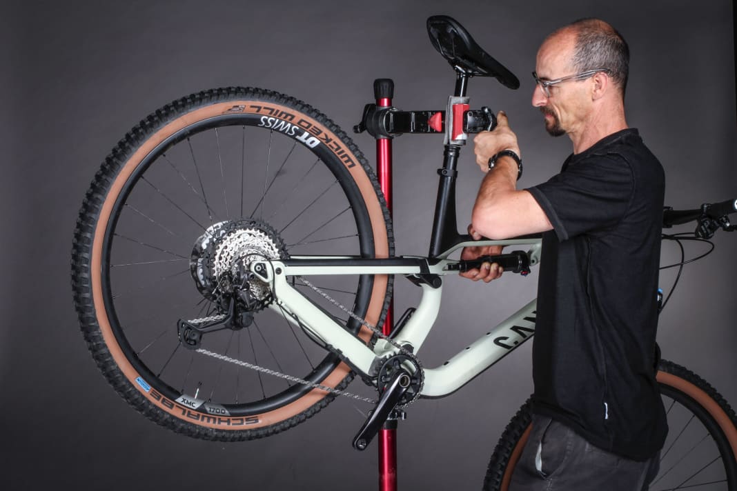 1. Bike aufhängen: Ein Montageständer ist ein idealer Helfer beim Einstellen der Schaltung. Wer keinen hat, hängt das Bike mit dem Sattel an eine Stange. So kann man mit der linken Hand an der Kurbel drehen und mit der rechten den Schalthebel bedienen.