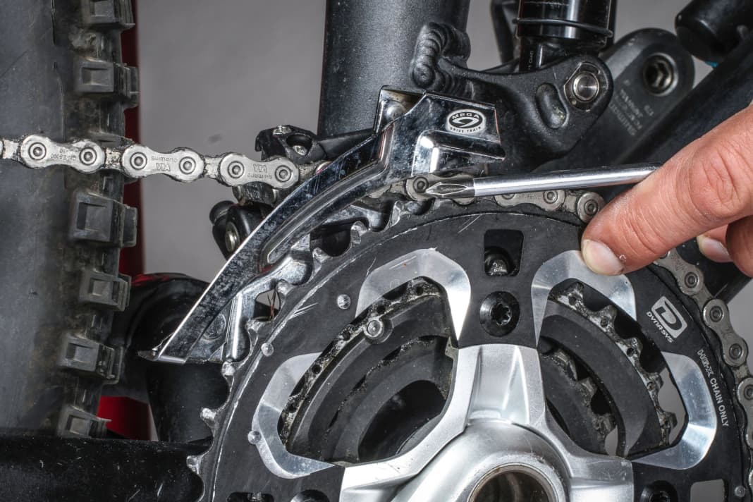 1. Höhenabstand: Wenn die Kette auf dem größten Kettenblatt liegt, sollten zwischen dem äußeren Leitblech und den Zähnen des großen Kettenblatts ein bis drei Millimeter Abstand sein. Die Dicke eines Zollstocksegments passt in der Regel gerade so zwischen Leitblech und großes Kettenblatt. Die Höhe des Umwerfers lässt sich mit Hilfe der Befestigungsschraube des Umwerfers am Rahmen einstellen.