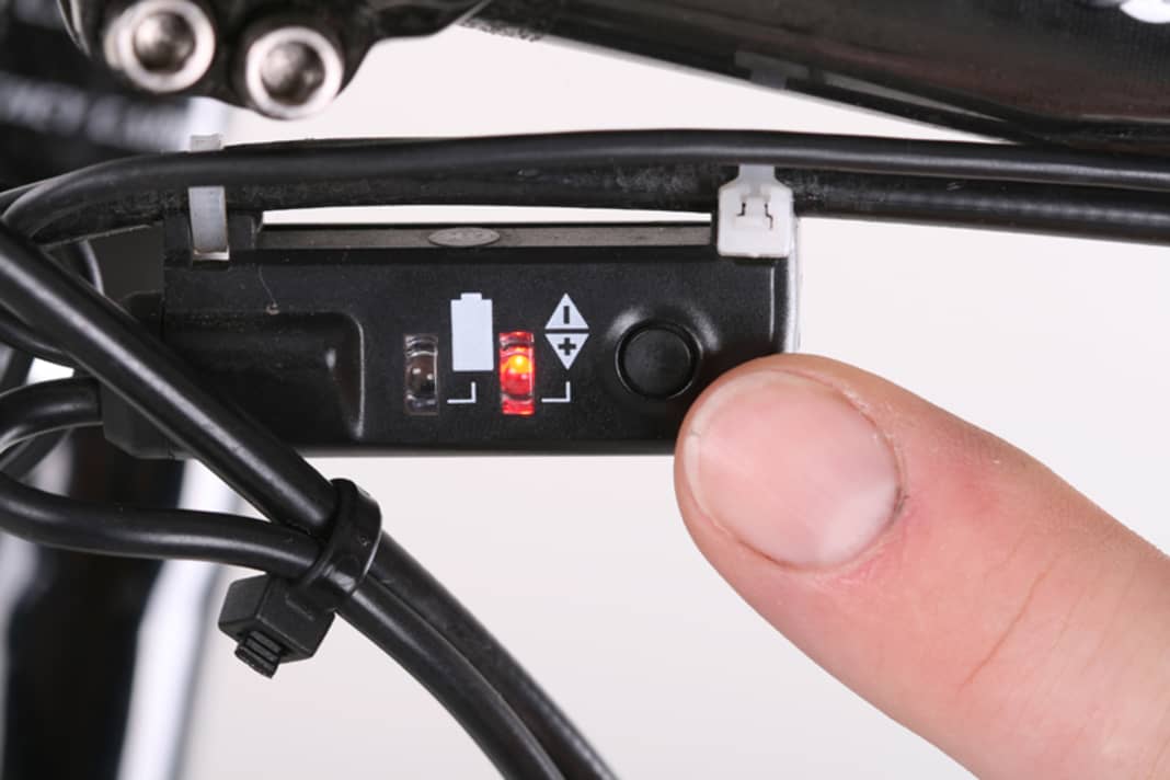 Schalten Sie auf einen mittleren Gang. Drücken Sie die Taste an der vorderen Weiche unter dem Lenker, bis die Kontrollleuchte rot aufleuchtet. Das Schaltwerk kann jetzt fein justiert werden. Drehen Sie an der Kurbel und lauschen Sie dem Lauf der Kette.