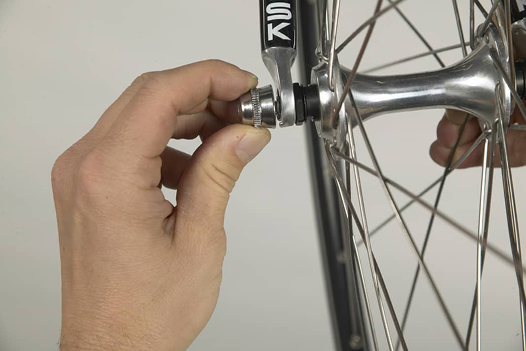 1. Beim Vorderrad müssen Sie anschließend die gegenseitige Mutter einige Umdrehungen öffnen, damit der Schnellspanner an den Ausfallsicherungen der Gabel vorbeigleiten kann.