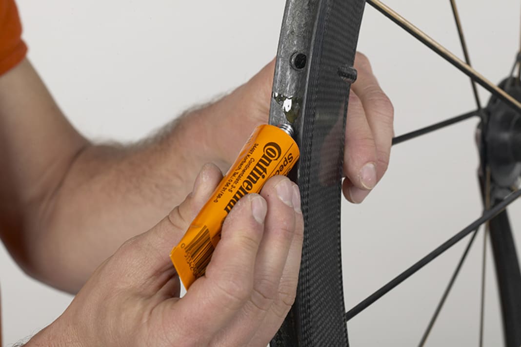 1. the easiest way to apply the glue is to clamp the wheel in a centring stand or in an old fork in a vice. If you are already experienced, you can glue directly from the tube; for everyone else, a brush with stiff bristles makes the job easier.