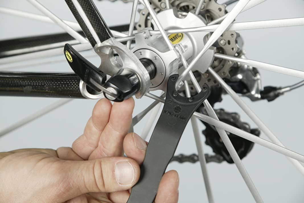 1. Das serienmäßige Mavic-Werkzeug hat Zapfen, die in Vertiefungen der seitlichen Abdeckung aller Mavic-Laufräder eingreifen. Setzen Sie das Werkzeug so an, dass alle Zapfen greifen. Drehen Sie wenige Winkelgrade im Uhrzeigersinn, um das Spiel zu verringern und in die andere Richtung, um etwas mehr Lagerluft zu erreichen. 