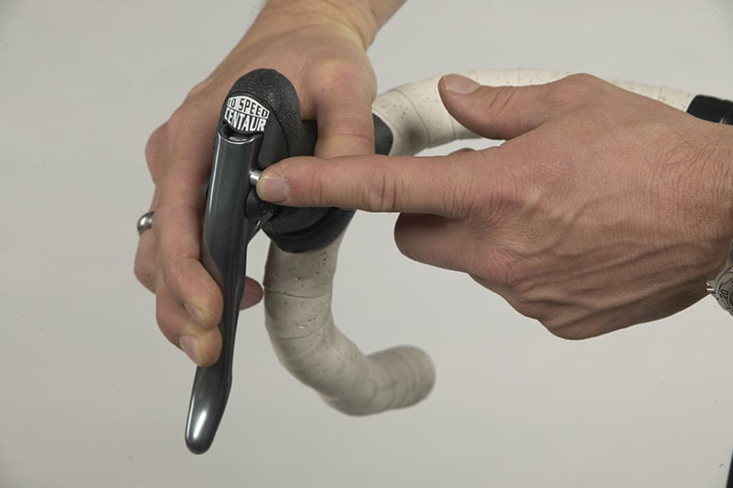 1. Öffnen Sie die Bremse. Bei Campagnolo dient dazu der kleine Riegel im Ergopower- Schaltbremsgriff. Ziehen Sie den Bremshebel leicht und schieben Sie den Stift zur anderen Seite, also von innen nach außen.