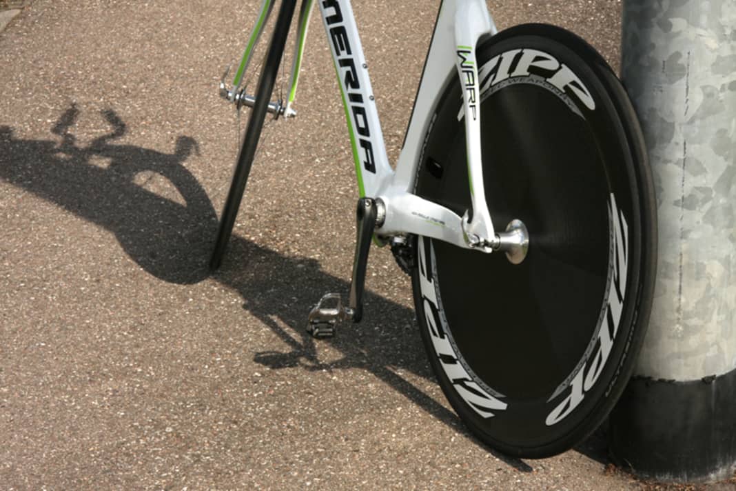 Lehnen Sie das Hinterrad gegen den Pfosten. Die Reibung des Reifens vermeidet, dass das Rennrad losrollt und kippt. Profimechaniker stellen so eine ganze Reihe von Rennmaschinen auf engstem Raum an einer Hauswand ab.