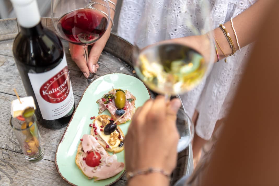 Ein Weinfass als Stehtisch, ein Snack und ein Glas Wein. Genießer sind in Kaltern am richtigen Ort.