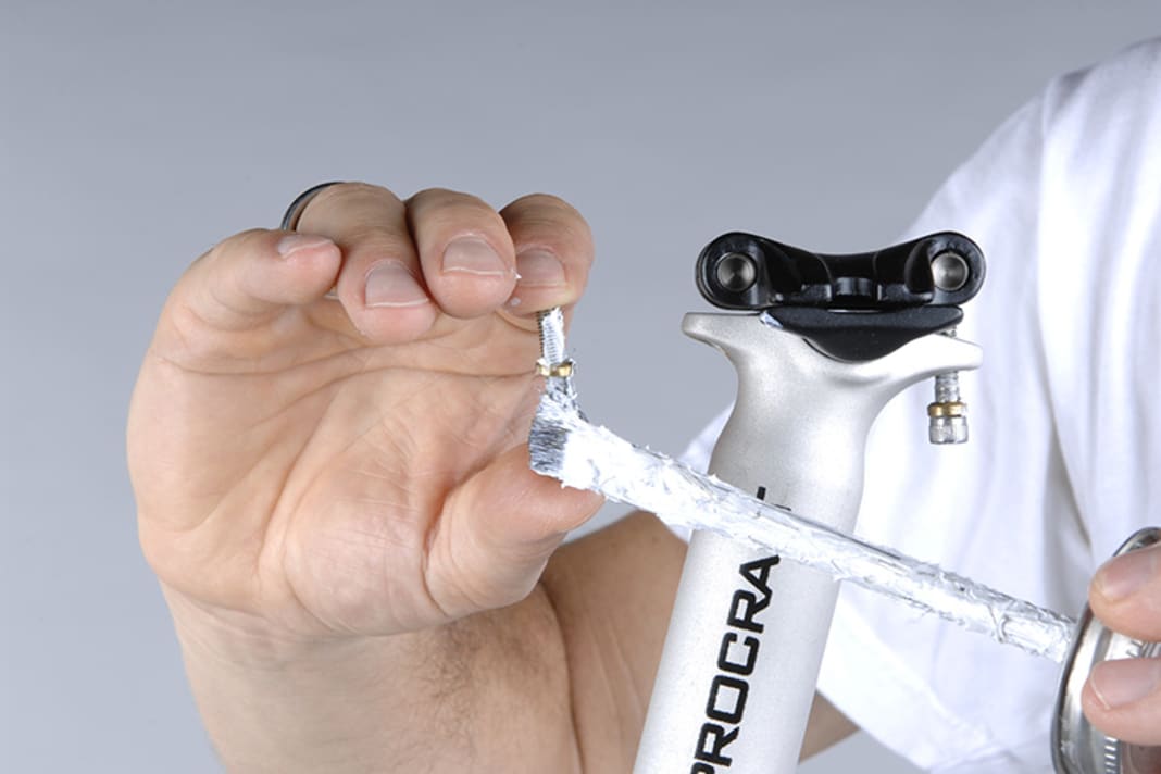 1. Auf der eigentlichen Stütze liegt eine bewegliche Halbschale, die das Sattelgestell aufnimmt. Die obere Halbschale wird über zwei Schrauben, die in Fahrtrichtung gesehen hintereinander liegen, nach unten gezogen. Wird die vordere Schraube eingedreht, senkt sich die Sattelnase ab, dreht man hinten, senkt sich das Heck. Lösen Sie zur Montage beide Schrauben gerade so weit, dass sie noch ins Gewinde greifen. Ungefettete Schrauben sollten Sie allerdings zuerst ganz ausbauen und an Gewinde und Kopfauflage fetten. Schieben Sie die untere Halbschale seitlich heraus, um das Sattelgestell unter die obere Halbschale zu platzieren.