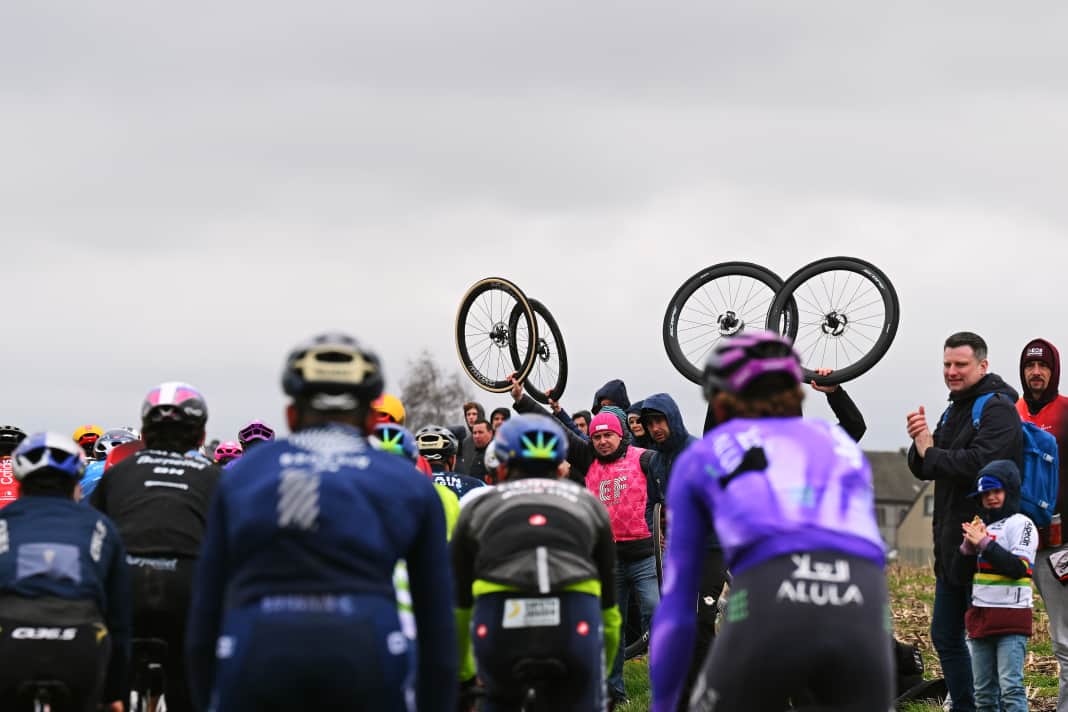 A typical picture at the classic races on cobblestones - the helpers hold their bikes in the air to draw attention to themselves