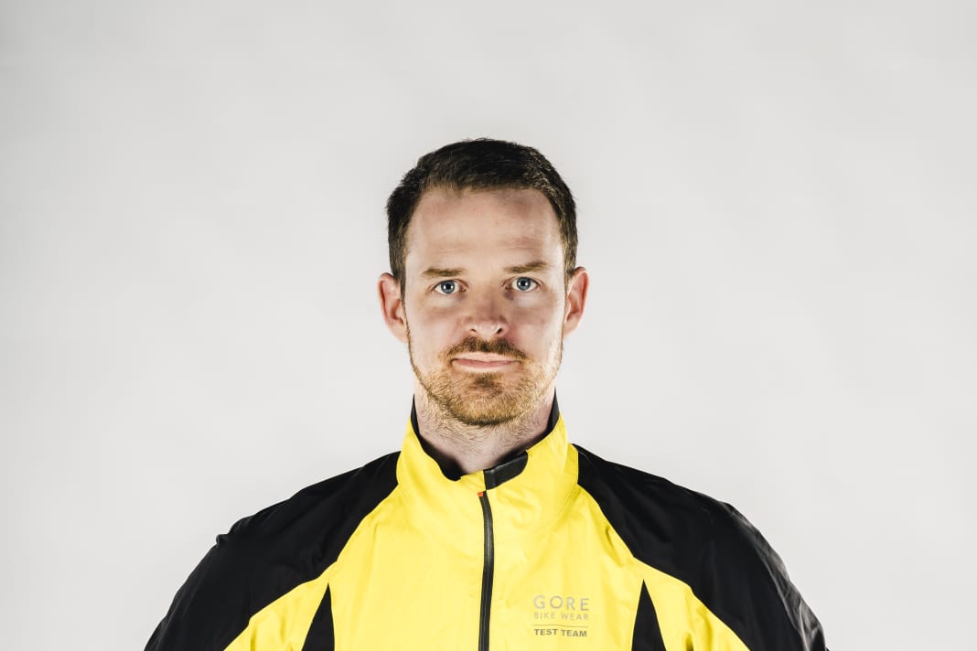 Der Schnitt der Regenjacke muss die gebeugte Haltung auf dem Rennrad vorwegnehmen und darf auch mal eine Nummer größer ausfallen, damit noch ein wärmendes Trikot darunter passt