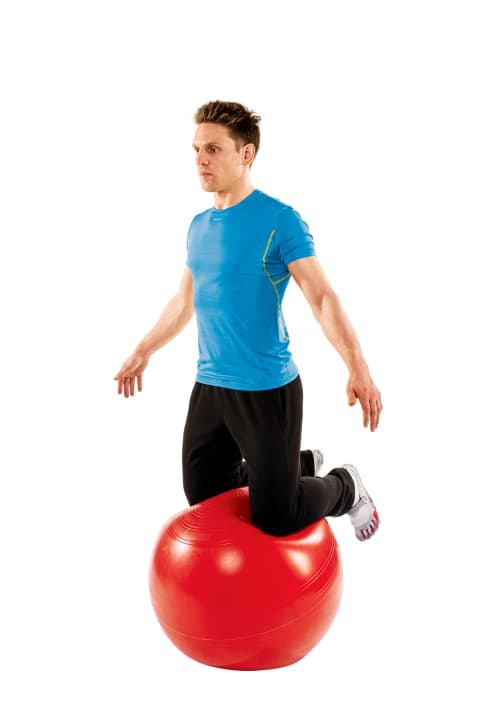   Kneel on the ball: 1. place both hands on the ball - about shoulder-width apart. Now step onto the ball with one knee. Then lift the other onto it. 2. now release your hands from the ball and straighten up. Your gaze is straight. Your buttocks do not touch the ball. Try to stay in this position for 60 seconds. Then take a break for 30 seconds and do two more sets.