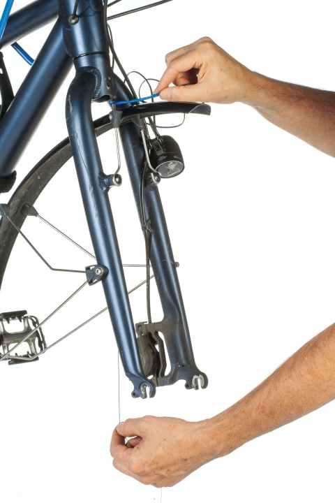 Verkleben Sie das neue Dynamokabel stabil mit dem Faden im Gabelholm. Führen Sie das Kabel langsam von oben nach, während Sie ihm durch behutsames Ziehen am Faden unten aus der Öffnung des Gabelholms helfen.