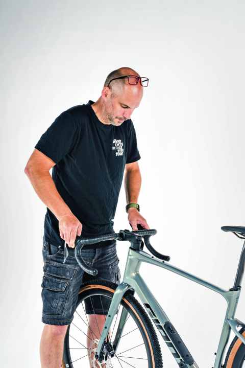 Kontrolle des Lenkers und des Vorbaus: Fassen Sie im Stand den Lenker an den Bremsgriffen, drücken und ziehen Sie abwechselnd.