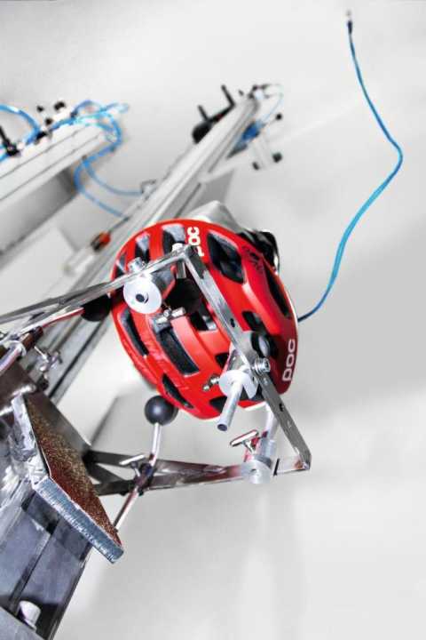 Der behelmte Prüfkopf, kurz vor dem seitlichen Aufschlag auf die geneigte Aufprallfläche.