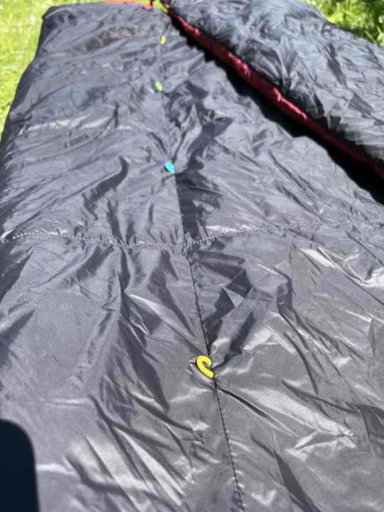 Mit diesem System aus bunten Haken und Ösen, lässt sich das Quilt in einen Schlafsack verwandeln.