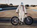 Das Design des streng limitierten Mondraker Dusty X E-Gravelbike mit Flatbar lehnt sich an die legendären Rennanzüge des Gulf-Racing-Teams an.