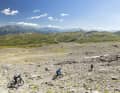 After the rocky terrain, the trail winds its way through lush alpine meadows. The panoramic view remains.