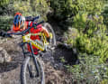 Seitliches Tragen: Man greift das Bike mit dem äußeren Arm an den Kettenstreben und legt sich die Sattelnase auf die Schulter. Das entlastet den Arm, und man kann kontrollierter gehen. Den Gegendruck gibt man auf das hangseitige Lenkerende. Wichtig: Positionieren Sie aus Sicherheitsgründen das Bike auf der hangabgewandten Seite.