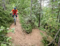 Mit Nachdruck in die Kurve: An dieser Stelle mag man sich fragen, was das mit E-MTB-Fahrtechnik zu tun hat. Aber eine ganze Menge! Den Unterschied machen das Mehrgewicht und der tiefe Schwerpunkt. Das bedeutet etwas Umstellung in Kurven, die so eng sind, dass man das Hinterrad versetzen muss.
 Das Anlupfen des Hinterrades vergleiche ich mit dem Spielchen, die hinteren beiden Stuhlbeine eines Stuhls anzulupfen, während man die Lehne nach vorne drückt. Und genau das ist der entscheidende Punkt. Je mehr man die Sitzfläche entlastet, desto einfacher fällt das Führen mit der Lehne.
 Aufs Bike übertragen: Je stärker der Impuls nach vorne die Pedale entlastet, desto leichter fällt das Führen mit dem Lenker. Angefahren wird die Kurve von außen nach innen (Bild 1).
