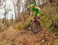 Approach: You should already scan the bend on the approach. How tight is it, what is the surface like, what is the exit like? Reduce your speed to walking pace. Fix the point at which you want to bring the front wheel to a stop. Your legs and arms are slightly bent. The body position is central, the saddle is fully lowered. | WRONG: Body position too rear-heavy, resulting in loss of control
