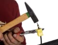 Schieben Sie nun die Schutzkappe, die Befestigungsschraube und den Klemmring in dieser Reihenfolge auf die Leitung. Legen Sie die Bremsleitung zwischen die gelben Klemmbacken und fixieren Sie diese mit einer Rohrzange. Danach schlagen Sie die Stützhülse mit einem Hammer vorsichtig in die Leitung ein.
