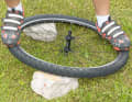 CAPITAL EIGHT

The wheel is not only distorted by broken spokes. Extreme lateral loads or an impact at high speed can cause the wheel to "chip". In order to be able to continue the tour anyway, you should push the "figure eight" out of the wheel. To do this, place the wheel on something solid, such as stones as shown in the picture. The points where the rim bends should be supported. Stand with one foot on the straight side of the rim. Put weight on the bent side with the other foot. Check the success and repeat the process if necessary. Tip: Works best in pairs. You may have to remove the rim brake to continue riding, but at least the wheel will fit through the fork. Have it checked at home by a specialist.