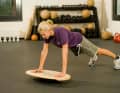 3. Instabiler Liegestütz
Nehmen Sie die klassische Liegestützstellung ein. Positionieren Sie die Hände etwas über schulterbreit auf das Wackelbrett. Die Füße in gleicher Breite aufstellen. Bauch und Po anspannen. Führen Sie jetzt einen Liegestütz aus.