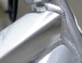Raw material:
Polished or brushed aluminium or titanium can look great, but only retain the look permanently with a thin layer of paint (otherwise you have to polish frequently). Advantage: Weight and cost. Steel, carbon or magnesium cannot be left untreated (corrosion).