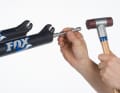 Place the nut on top and carefully tap with a hammer until the standpipes inside the fork come loose from the dip tubes. Remove the nuts and the washers underneath.