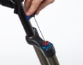 Verstellkappen abschrauben: Drehen Sie die Zugstufendämpfung (rotes Einstellrad) ganz auf. Schrauben Sie den Einstellknopf mit einem 2-Millimeter-Inbus-Schlüssel ab.