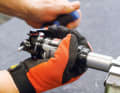 2. open the housing First remove the red SAG ring from the piston rod and clamp the damper in a vice with protective jaws as shown in the picture. Using rubberised gloves (or an oil filter strap spanner), the damper sleeve can be completely unscrewed anti-clockwise while holding it in place with an Allen key.
