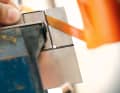 Die Form mit einer Metallsäge (alternativ Blechschere) aussägen. Um saubere Ecken zu bekommen, diese vorbohren. Die Kanten werden mit einer Metallfeile entgratet, die Ecken abgerundet. Dazu spannt man den Blech-Rohling am besten in den Schraubstock.