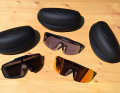 Three fresh pairs of sunglasses from Italy lie on a wooden board.