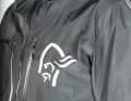 Das große Norrøna Logo reflektiert, so wie alle anderen hellen Applikationen auf der Norrøna fjørå Regenjacke..