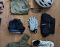 Voici les affaires pour le vélo : un casque et des lunettes Julbo, un pantalon, un t-shirt, des chaussettes et des gants GripGrab, ainsi que des chaussures pour le gravel, une ceinture cardiofréquencemètre et une brassière de sport Mérinoi décontractée.