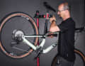 1. Bike aufhängen: Ein Montageständer ist ein idealer Helfer beim Einstellen der Schaltung. Wer keinen hat, hängt das Bike mit dem Sattel an eine Stange. So kann man mit der linken Hand an der Kurbel drehen und mit der rechten den Schalthebel bedienen.