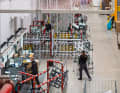 High above the heads of the employees, frames and wheels hover for assembly.