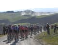 Das Feld auf einer der vielen Schotterpassagen in toskanischer Hügellandschaft bei den Strade Bianche der Männer, 4. März 2023.