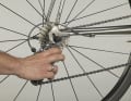  4. grasp the rear derailleur at the front of the parallelogram and press on the cage of the rear derailleur with your thumb so that it releases the space for the sprocket set - the axle slides into the dropouts. Continue to hold the frame firmly and pull the wheel all the way into the axle mounts. Check that the rim is centred between the rear stays and close the quick release and brake release lever.