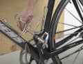 2 Unscrew the pedals on the wheel. The right pedal opens anti-clockwise, the left pedal has a left-hand thread, so it must be opened clockwise. Caution: Pedals come off abruptly - use an offset spanner and position it so that your hand is away from the chainring teeth when loosening the screw connection.